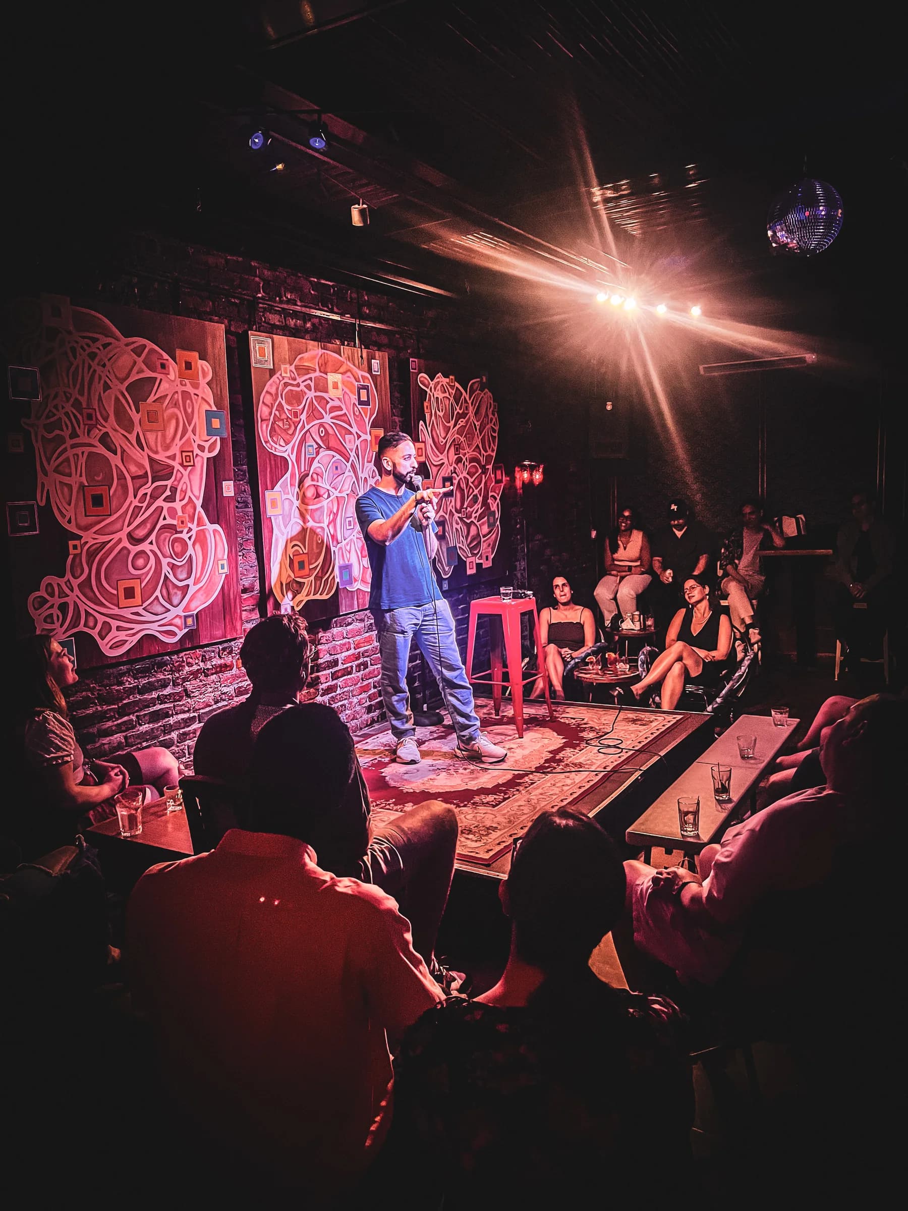 The stage lights illuminate a comedian and audience at The Setup’s NYC show